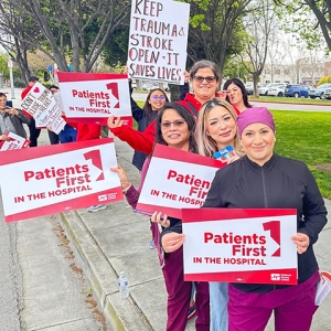 Nurses outside holding signs "Patients First in the Community"