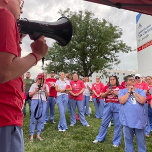 Nurses in front of Ascension Via Christi hospital, listening to nurse speaking through megaphone