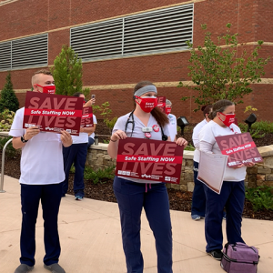 Nurses outside mission hospital hold signs calling for safe staffing