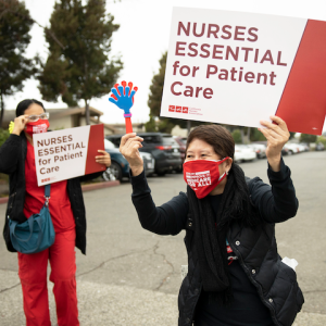 Nurses hold signs "Nurses essential for patient care"