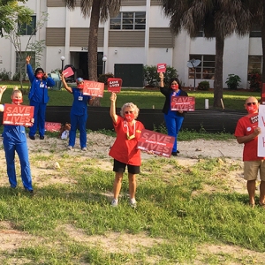 Nurses outside hospital holding various "Save Lives" signs