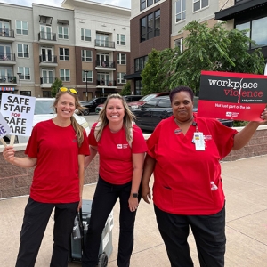 Three nurses holding signs calling for safety from workplace violence