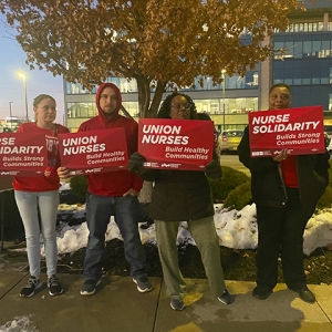 Four nurses outside Research Medical Center holding signs "Union Nurses Build Healthy Communities"