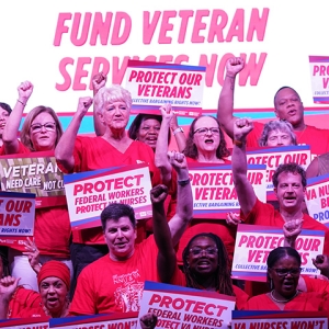 Group of nurses with raised fists holding signs supporting veterans and VA nurses