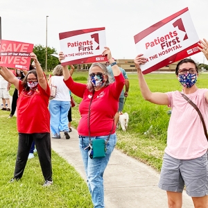 Nurses holding signs "Patients Firsts" and "Save Lives: Hands Off Our Ratios"