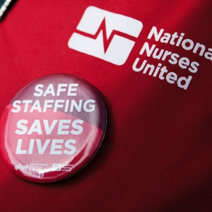 Red scrub with button "Safe Staffing Saves Lives"