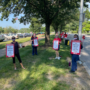 Nurses hold sign with various demands from HCA