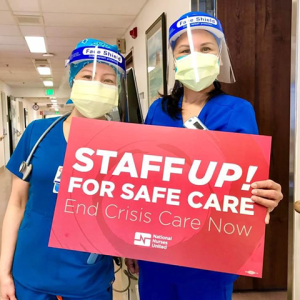 Two nurses holding sign: Staff up for safe care, end crisis care now