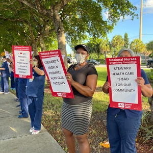 Nurses outside hold signs criticizing Steward Health's treatment of their patients