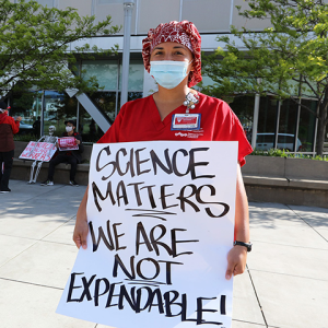 Nurse holds sign "Science Matters, We Are Not Expendable"