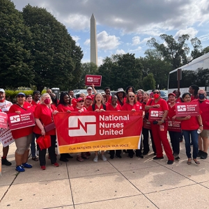 Large group of nurses holding "National Nurses United" banner in front of Washington Mounument