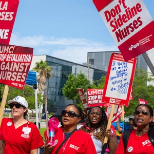 Nurses standing outside, holding signs calling for a fair contract