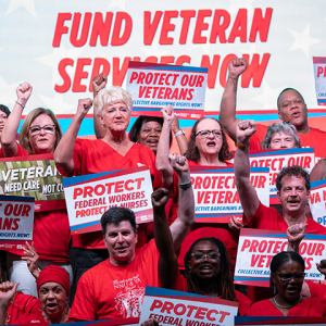 Group of nurses with raised fists holding signs supporting veterans and VA nurses