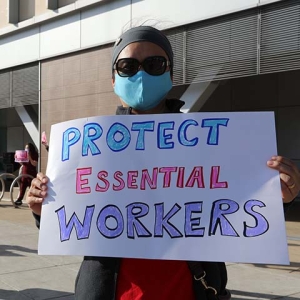 Nurse holds sign "Protect Essential Workers"