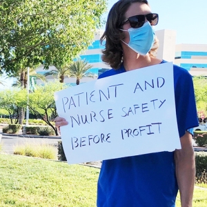 Nurse holding sign "Patient and nurse safety before profit"