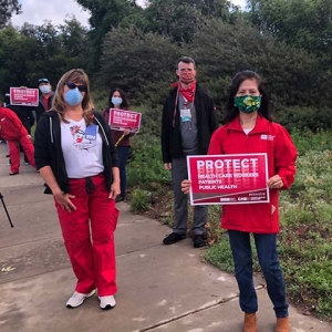 Health care workers hold signs calling for patient safety