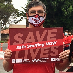 Nurse holding sign at rally "Save Lives: Safe Staffing Now"