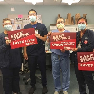 Nurse in hospital hold signs "Safe Staffing Saves Lives"