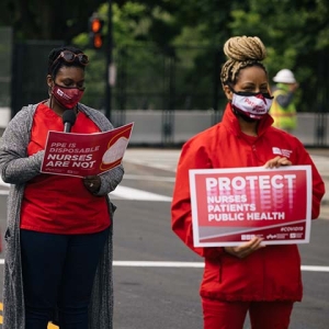 Nurses outside hold signs "Protect Nurses, Patients, Public Health"