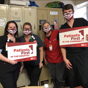 Four nurses inside hospital hold signs "Patients First"