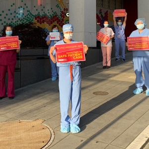 Nurses in front of Chinese Hospital with signs "Nurses fight for safe patient care"