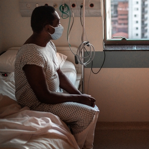 Patient of color looking out of hospital window 