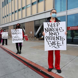 Nurses outside hospital hold signs "Keep nurses and patients safe"