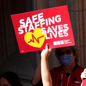 Nurse holding sign that reads "Safe staffing Saves Lives"