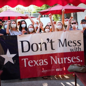 Large group of nurses outside hold sign "Don't mess with Texas nurses"