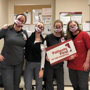 Four nurses inside hospital hold signs "Patients First"