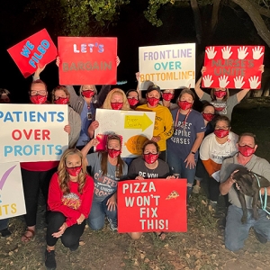 Group of nurses outside holding signs showing enthusiasm for organizing