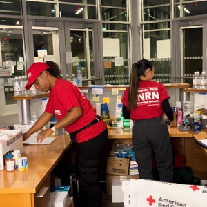 Two nurses inside hospital wearing RNRN shirts and hats preparing clinic