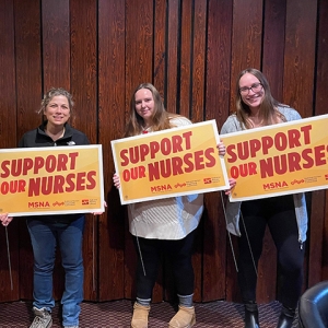 Four nurses inside holding signs "Support Our Nurses"