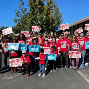 Large group of nurses and other canvassers holding signs "YES on Prop 50"