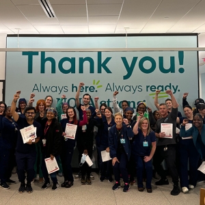 Large group of nurses inside hospital smiling, with raised fists
