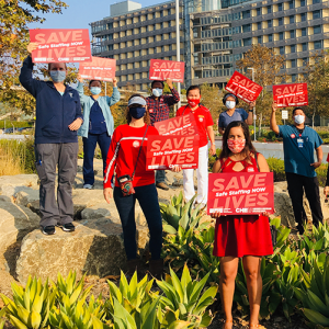 Health care workers hold signs calling fo safe staffing