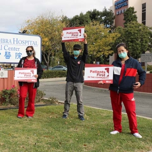 Nurses in front of Alhambra Hospital Medical Center sign hold signs calling for safe staffing and patient safety