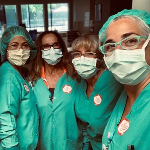 Four masked nurses inside hospital stand close together