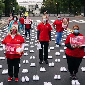 Group of nurses outside of The Whitehouse hold signs calling for permanent protection Covid measures