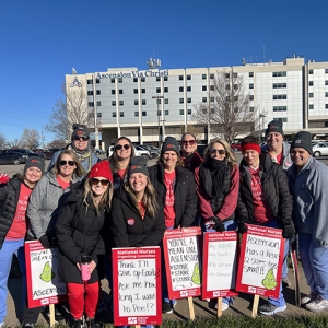 Group of nurses outside hospital holding picket signs