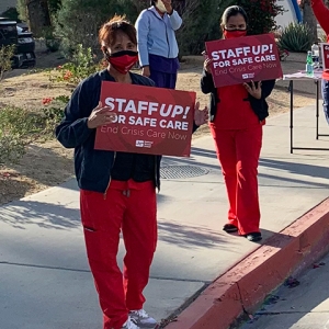 Nurses holding signs "Staff UP for safe care. End Crisis Care Now"