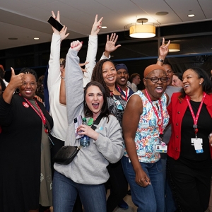 Large group of nurses celebrating with hands in the air