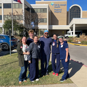 Six nurses outside hospital, smiling