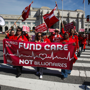 Nurses marching with banner "Fund Care NOT Billionaires"