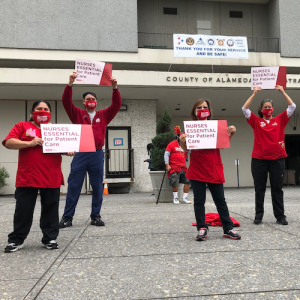 Nurses hold signs "Nurses Essential to Patient Care"