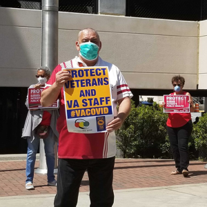 Nurses and hospital staff hold signs calling for prioritizing safety for staff anbd the public