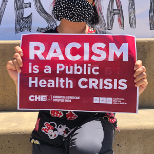 Nurse holds sign "Racism is a public health crisis"