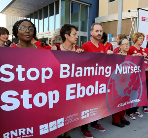 Large group of nurses holding sign "Stop Ebola Now"
