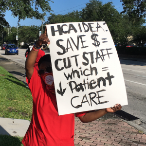 Nurse holds sign protesting HCA cost cutting measures