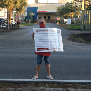 Nurses hold "COVID-19 checklist" signs outside Fawcett Memorial